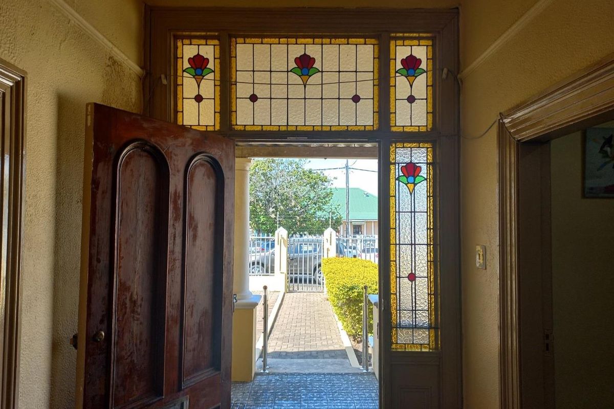 Entrance hallway featuring a classic timber front door with decorative stained glass transom and sidelight panels, providing a bright and welcoming transition into the home.