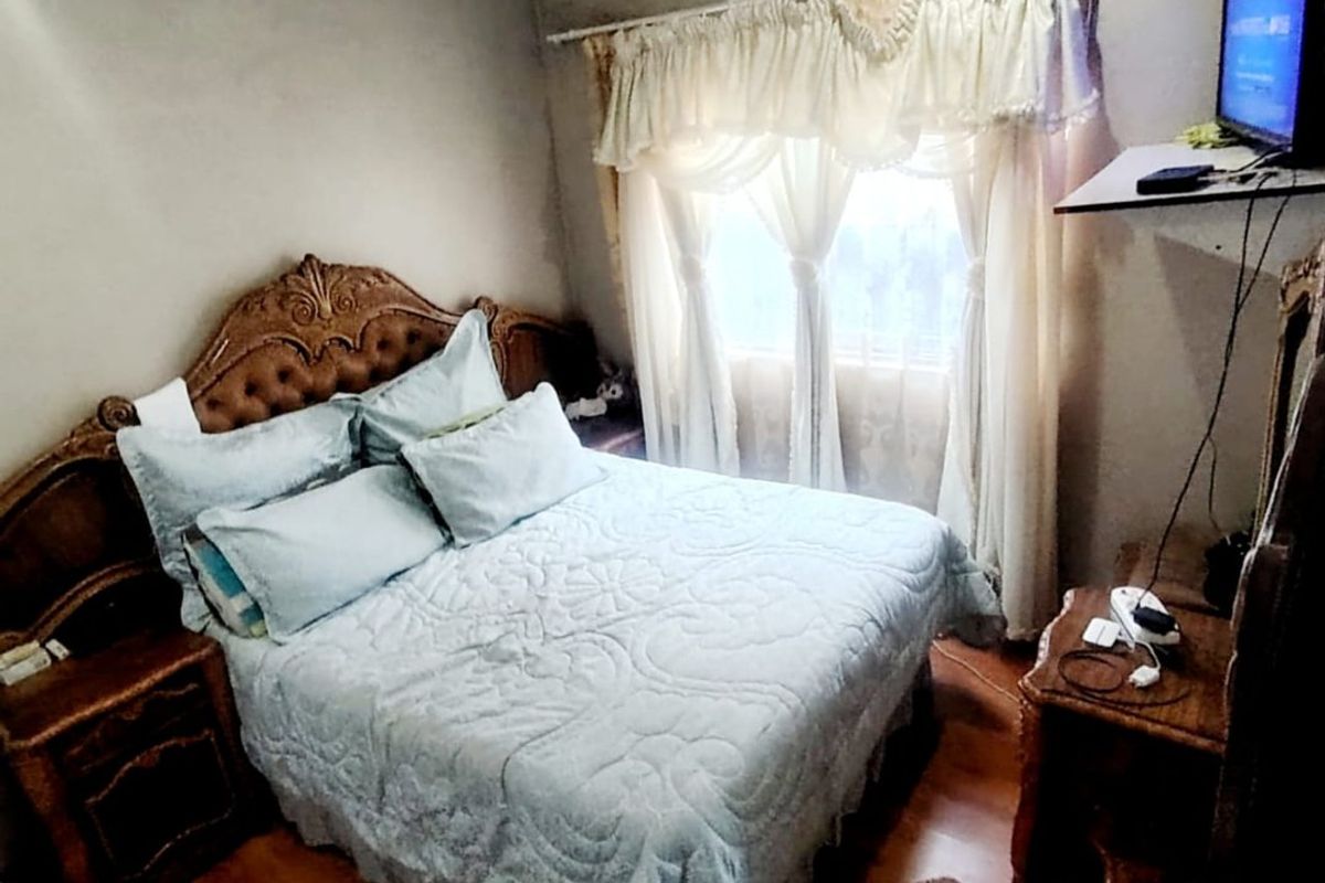 A compact bedroom featuring laminate flooring and decorative ceiling cornicing, offering a functional space with potential for modern updates.