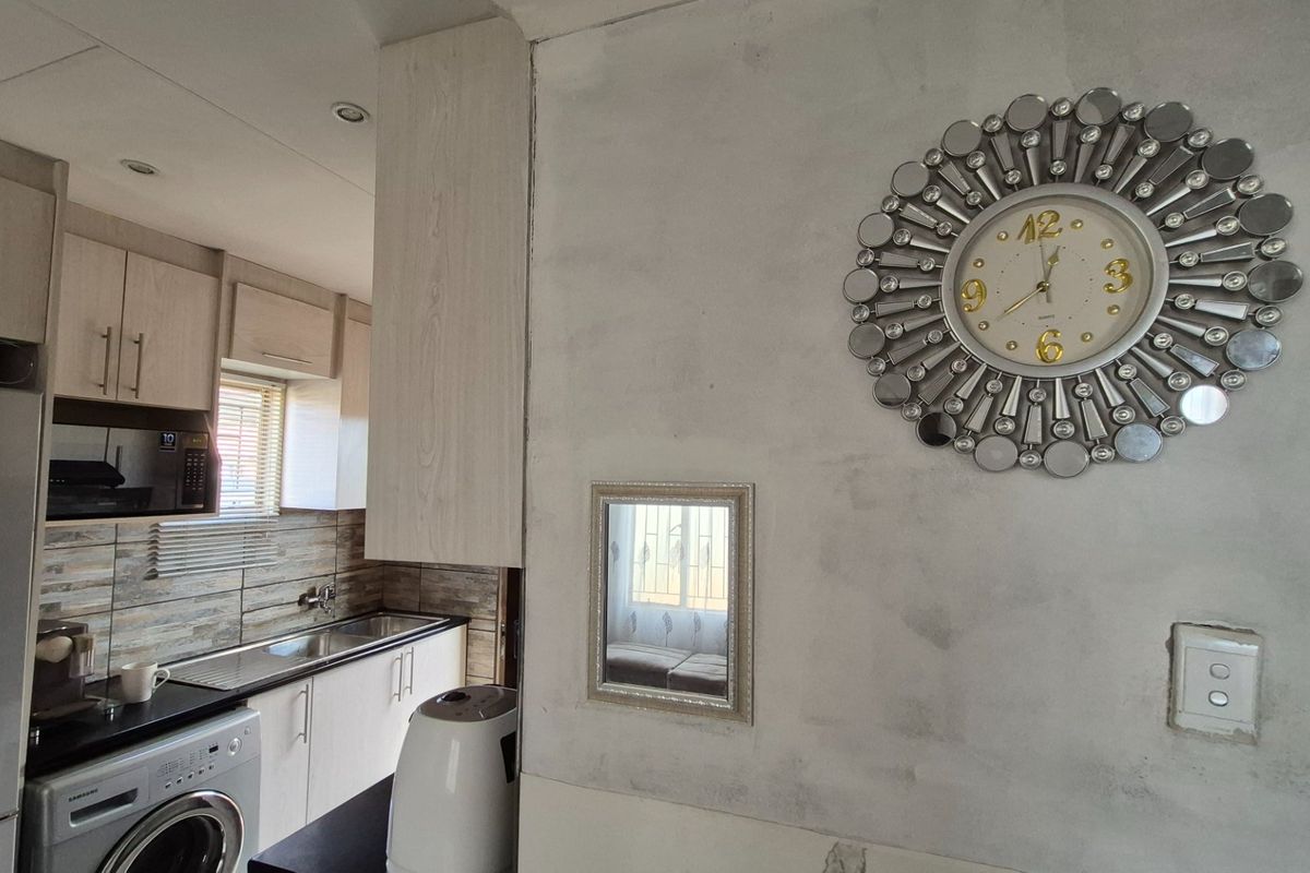 A compact kitchen area featuring built-in cabinetry, a stainless steel sink, and tiled backsplash, requiring finishing touches to the surrounding wall surfaces.