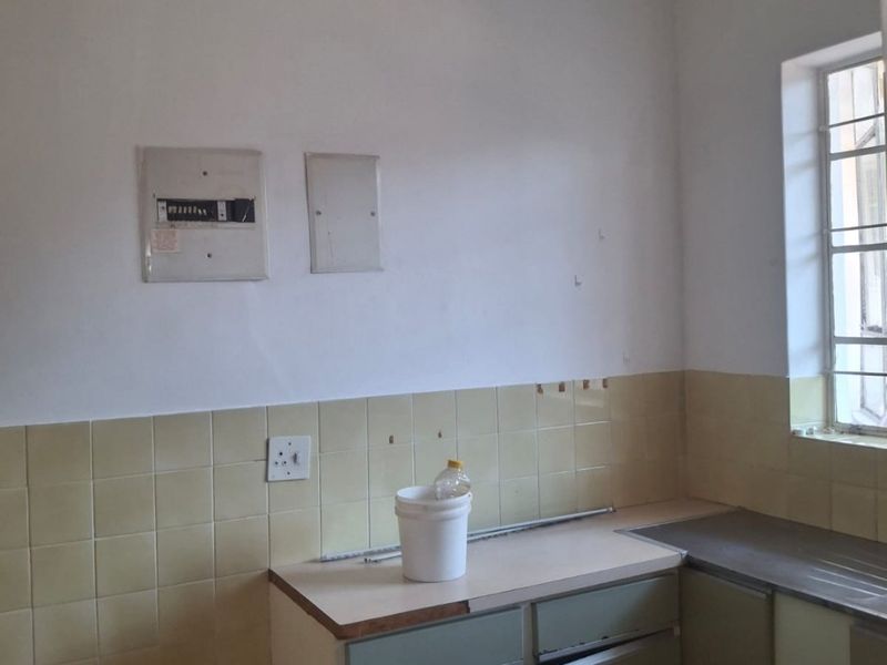 A dated kitchen featuring original cabinetry, tiled backsplash, and a built-in electric stove, offering significant potential for modernization and renovation.