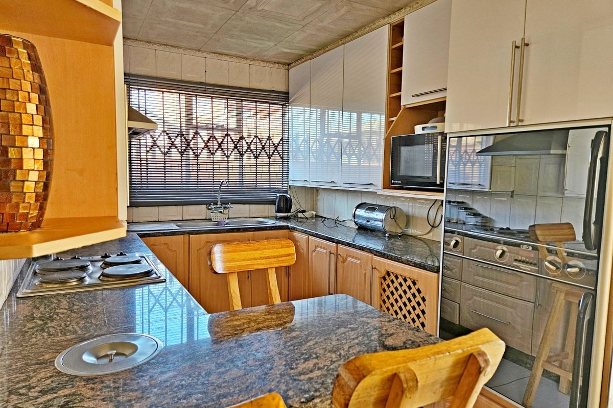 A functional kitchen featuring granite countertops, built-in oven, gas hob, and ample cabinetry, offering a practical layout for daily meal preparation.