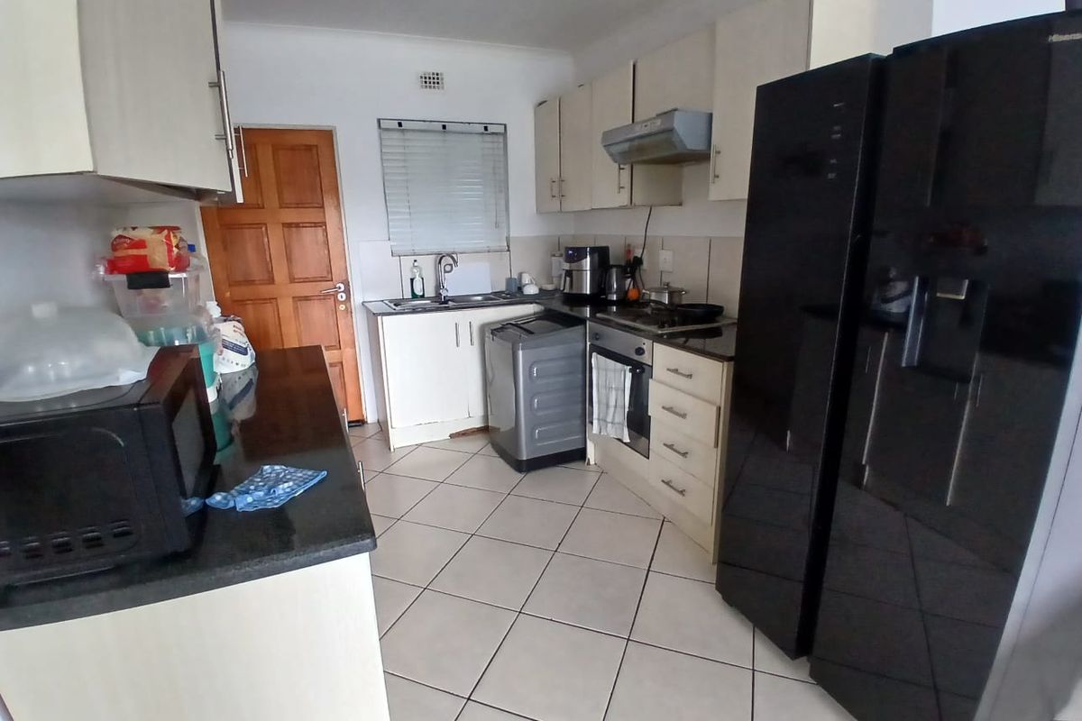 Functional kitchen featuring built-in cabinetry, granite countertops, integrated oven and hob, and tiled flooring, offering a practical layout for daily meal preparation.