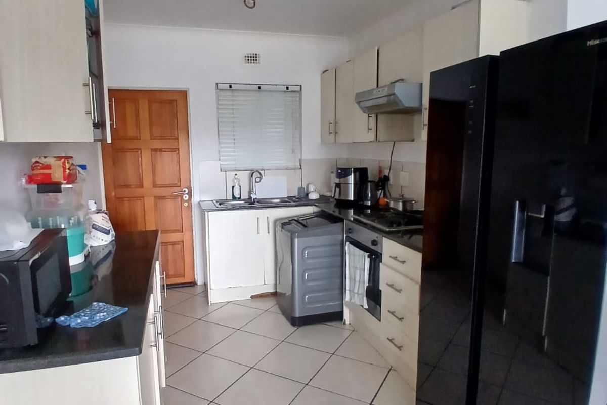 A functional kitchen featuring built-in cabinetry, dark countertops, tiled flooring, and integrated cooking appliances, offering a practical layout for daily meal preparation.