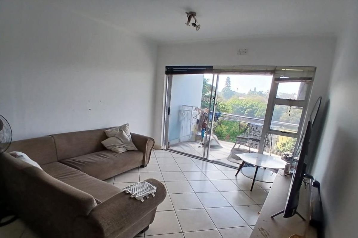 A living room featuring tiled flooring and a large sliding glass door providing access to an outdoor balcony area.