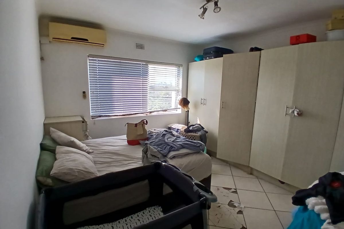 Bedroom featuring built-in cupboards, air conditioning, and venetian blinds. The room requires attention to the damaged floor tiles.