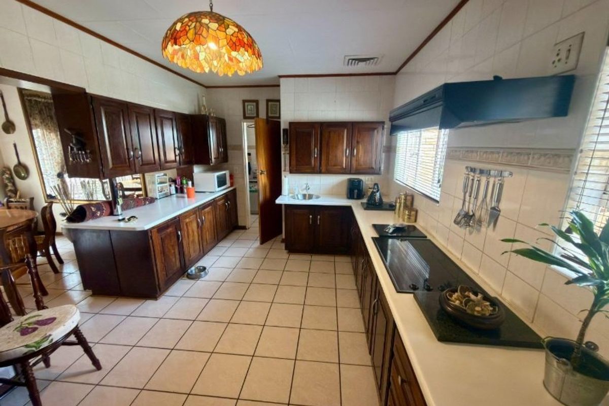 A spacious kitchen featuring dark wood cabinetry, ceramic tile flooring, and ample counter space, offering a functional layout with classic finishes.