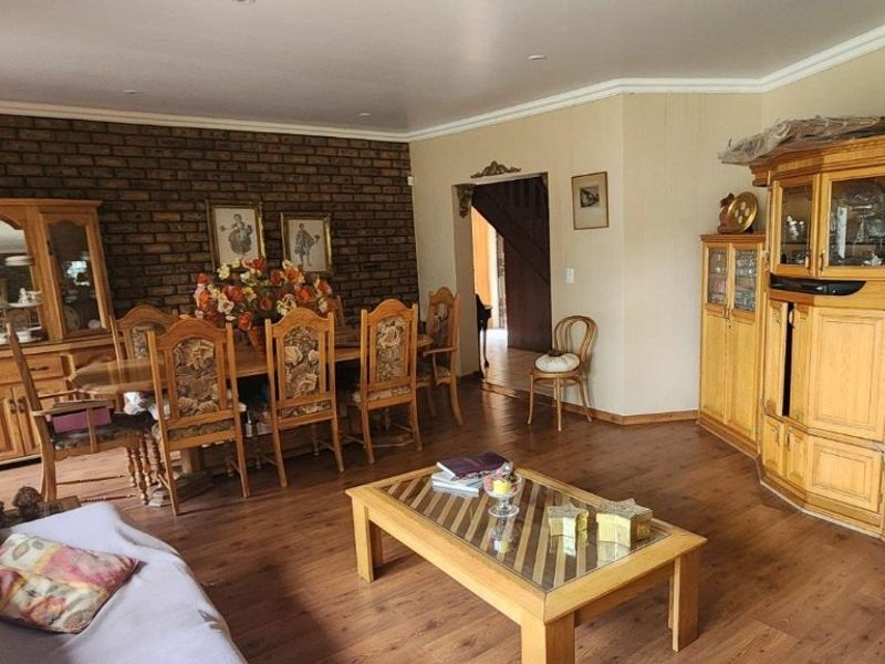 Spacious open-plan living and dining area featuring an exposed brick feature wall, laminate flooring, and coved cornicing throughout.