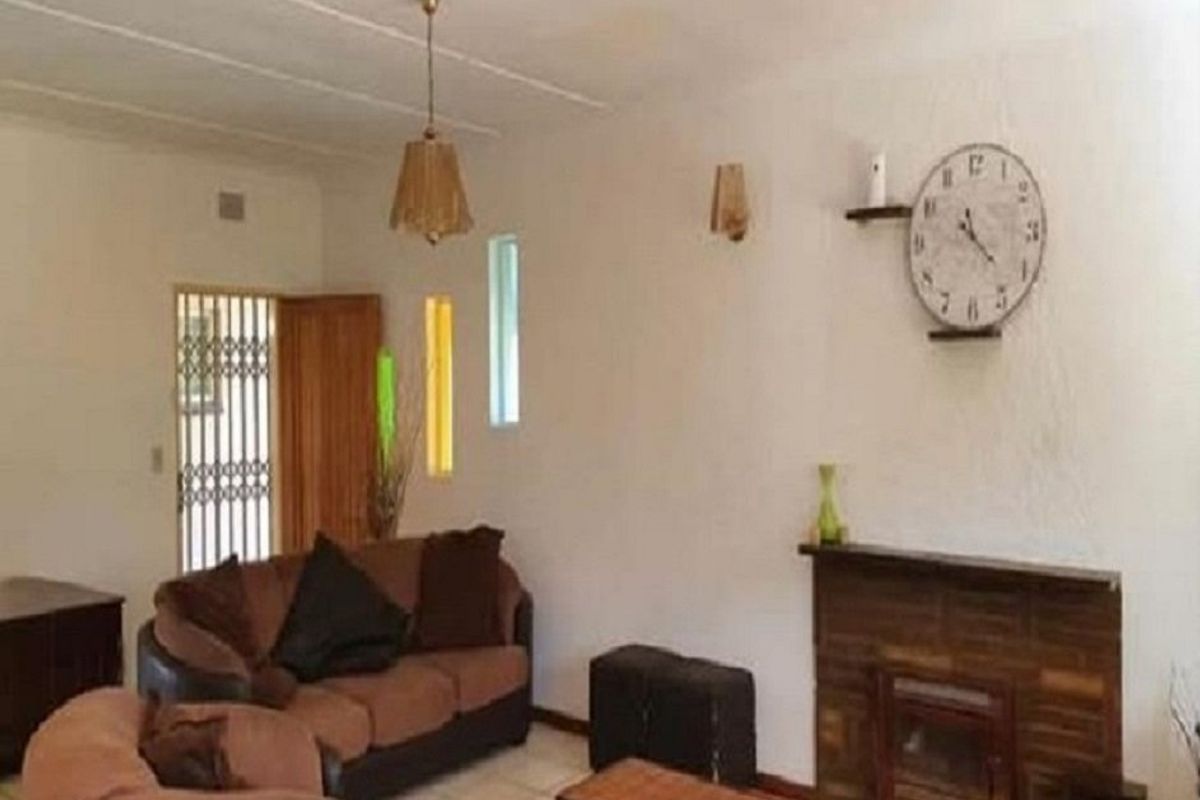 A living room featuring a brick fireplace, tiled flooring, and a security gate at the entrance.