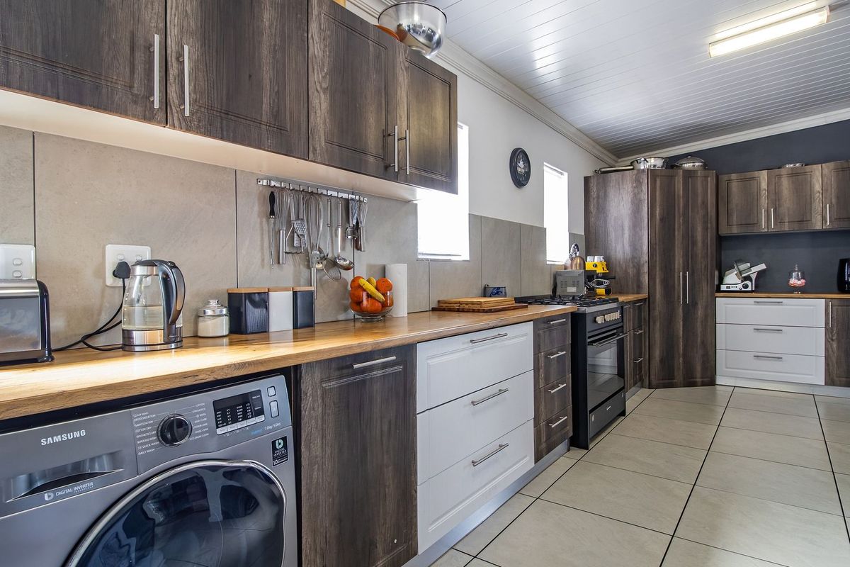 Modern kitchen featuring dark wood and white cabinetry, wooden countertops, tiled flooring, and a tongue and groove ceiling with integrated lighting.