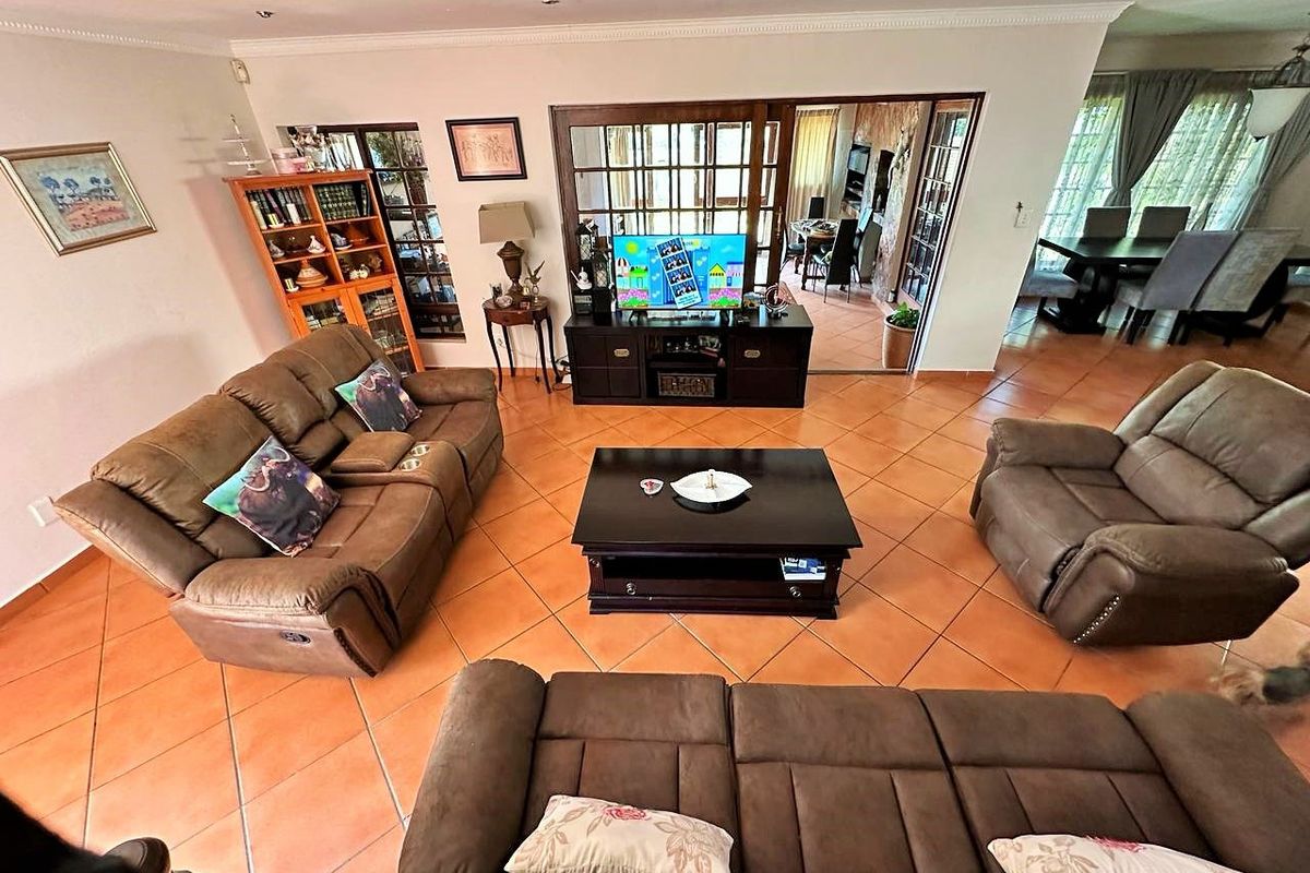 Spacious living room featuring terracotta floor tiles, recessed lighting, and sliding glass doors leading to an adjacent dining area.