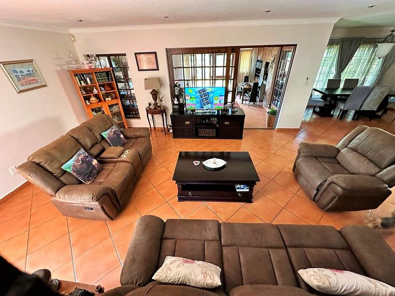 Spacious living room featuring terracotta floor tiles, recessed lighting, and sliding glass doors leading to an adjacent dining area.