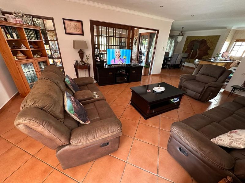 Spacious open-plan living area featuring terracotta floor tiles, coved cornicing, and timber-framed glass doors leading to adjacent spaces.