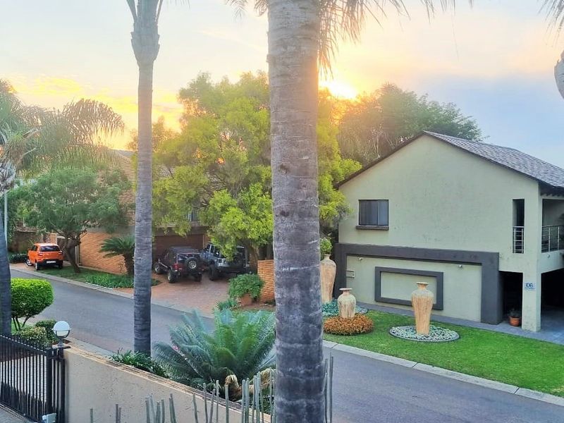 A street-level view of the property exterior, showcasing the driveway, landscaped garden, and building facade at sunset.