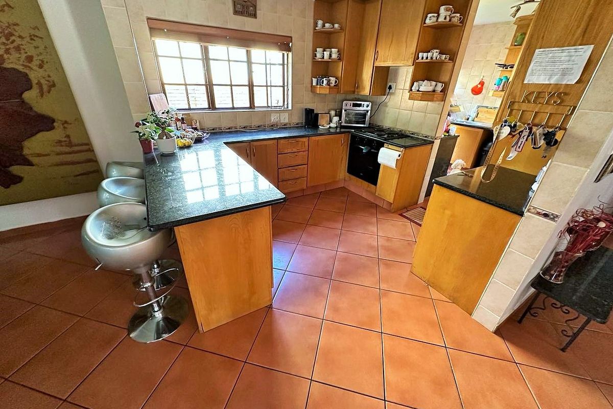 Functional kitchen featuring wooden cabinetry, granite countertops, a breakfast bar, and tiled flooring, offering a practical layout for daily meal preparation.