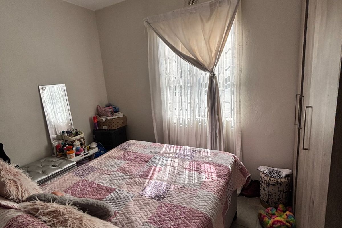 A functional bedroom featuring tiled flooring and a built-in wardrobe, offering a practical layout with natural light from the window.