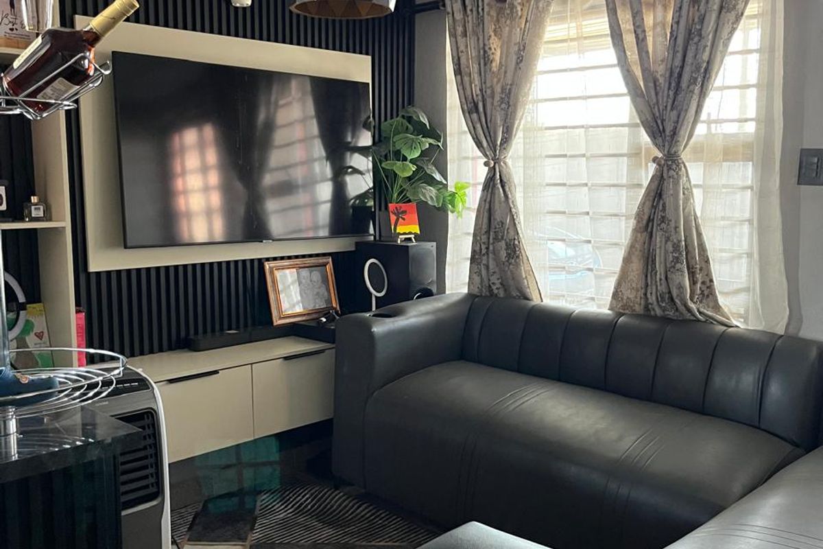 A compact living room featuring modern slatted wall paneling, a built-in media console, and a contemporary pendant light fixture.