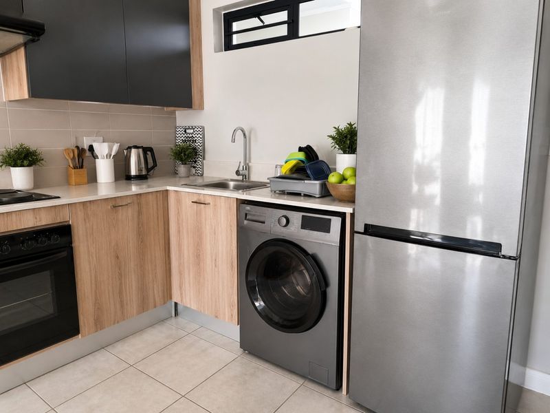 Modern kitchen featuring wood-finish cabinetry, dark upper cupboards, tiled backsplash, built-in oven, hob, and integrated space for a washing machine.