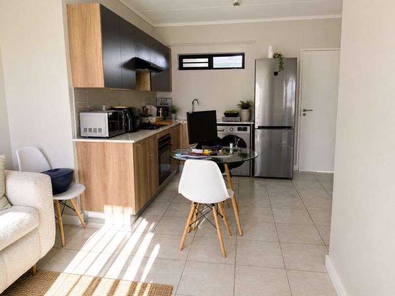 Modern open-plan kitchen featuring contemporary two-tone cabinetry, integrated appliances, and neutral tiled flooring, seamlessly connecting to the living area.
