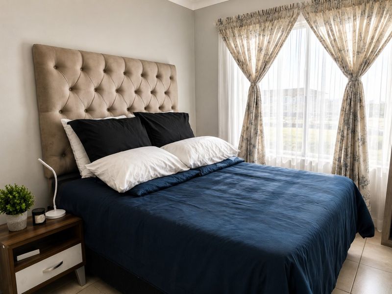 A well-maintained bedroom featuring neutral wall tones and tiled flooring, offering a comfortable and functional living space.