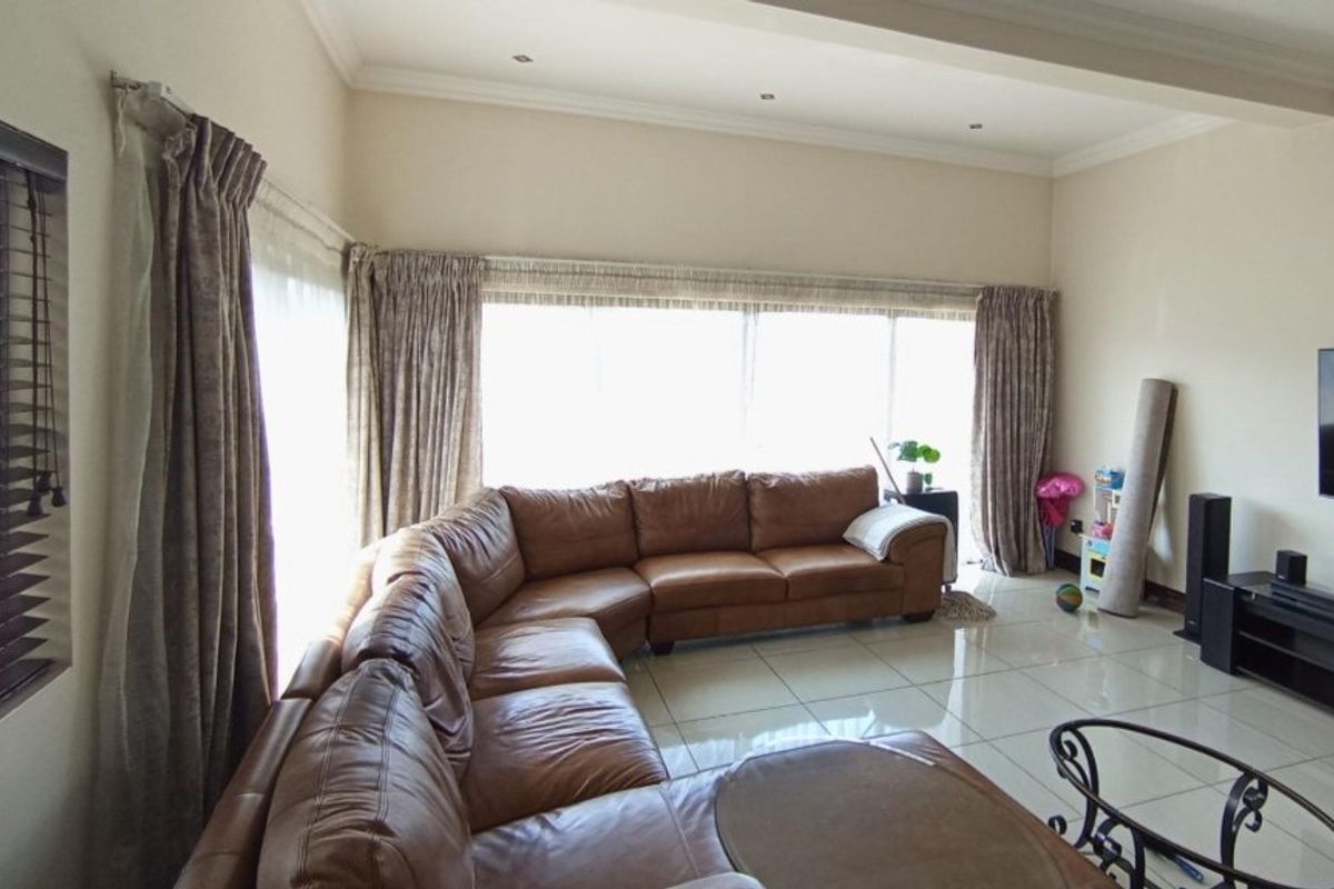 Spacious living room featuring large windows, tiled flooring, and recessed ceiling lighting, offering a bright and open atmosphere.