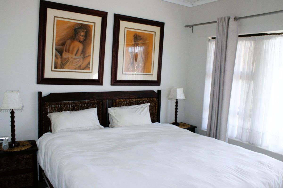 A well-maintained bedroom featuring neutral walls, natural light through window treatments, and a clean, functional layout.