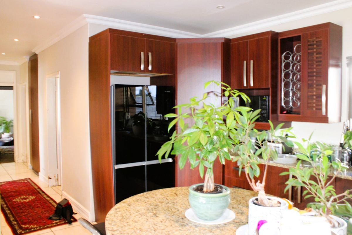 A functional kitchen featuring dark wood cabinetry, granite countertops, and integrated storage, including a dedicated wine rack and recessed ceiling lighting.