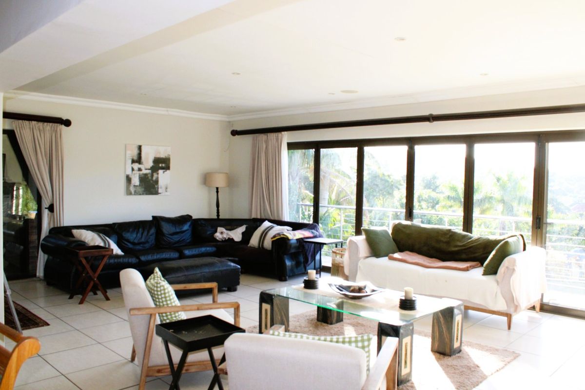 Spacious living room featuring large sliding glass doors that provide ample natural light and access to the outdoor area, complemented by neutral tiled flooring.