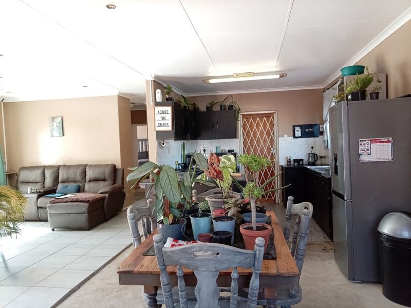 Open-plan living and kitchen area featuring tiled flooring, built-in cabinetry, and a security gate, offering a functional layout for daily living.