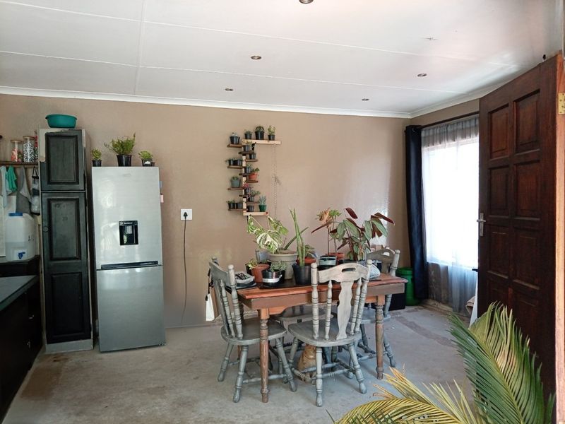 Open plan living and dining area featuring recessed downlights and direct access to the exterior via a timber door.