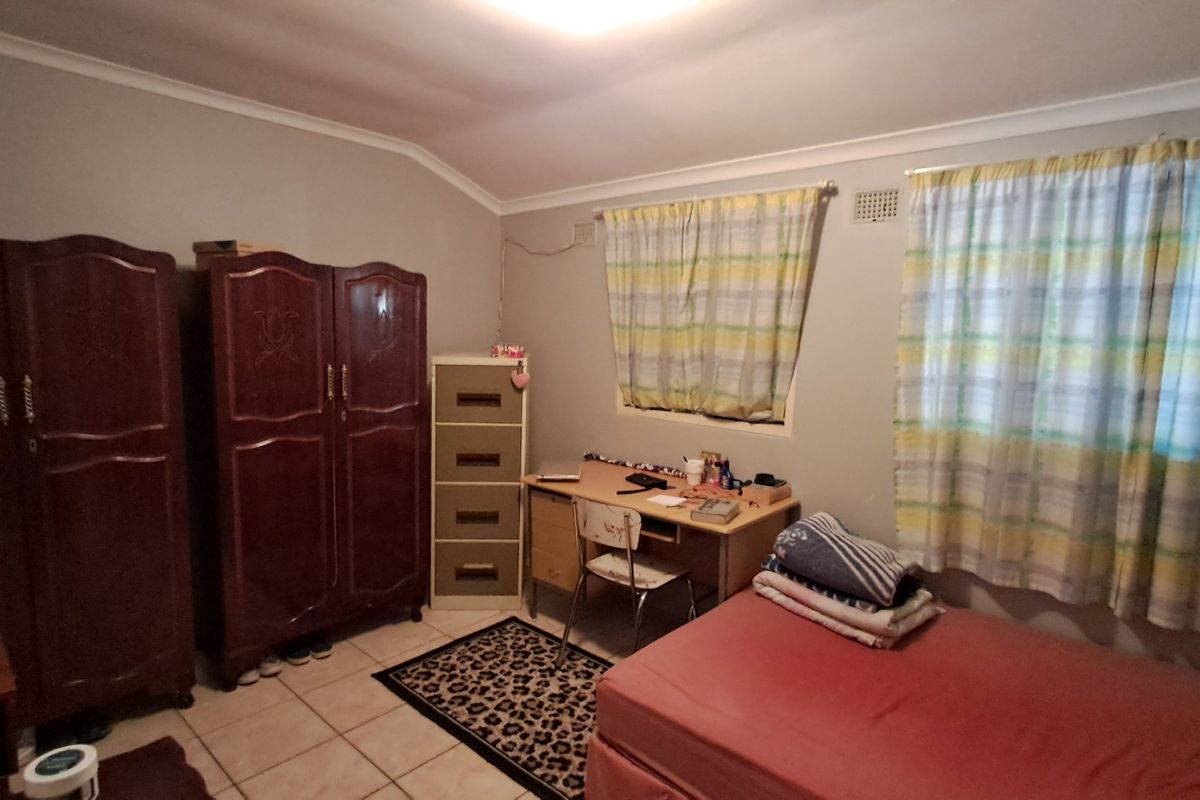 A functional bedroom featuring tiled flooring, coved ceilings, and natural light through dual windows.
