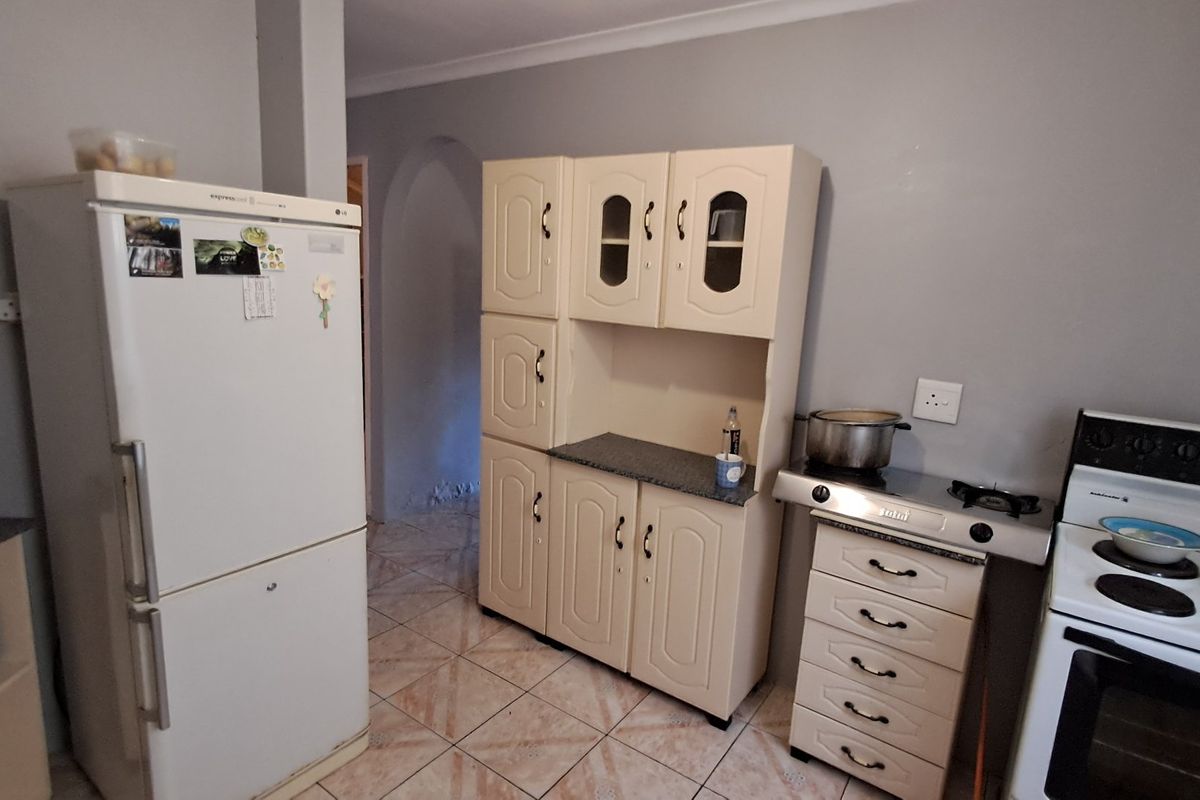 A functional kitchen area featuring built-in cabinetry, tiled flooring, and a freestanding stove, providing a practical space for meal preparation.