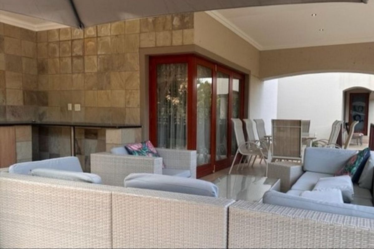 Covered outdoor patio featuring stone wall cladding, a built-in bar counter, and timber-framed folding doors leading into the main living area.