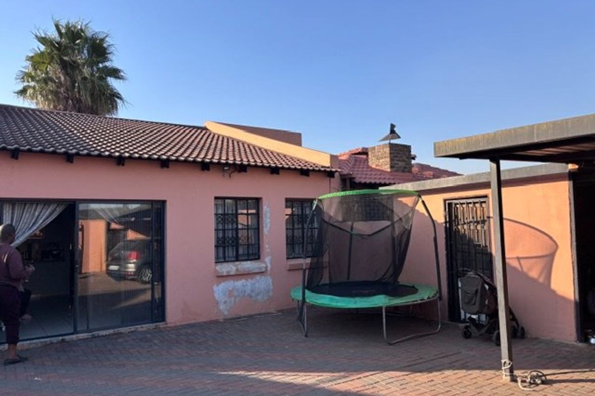 Rear exterior view of the house featuring brick paving, a tiled roof, and a sliding door entrance with visible exterior wall maintenance required.