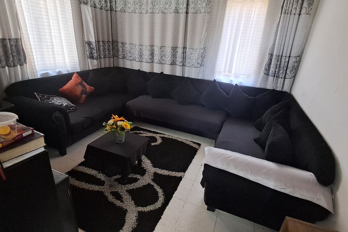 A living room area featuring tiled flooring and window treatments, providing a functional space for relaxation.