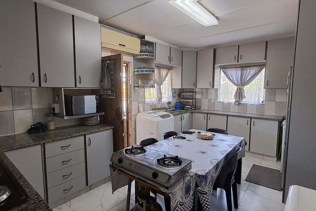 Functional kitchen featuring ample built-in cabinetry, granite countertops, tiled backsplash, and a double sink, offering a practical layout for daily meal preparation.