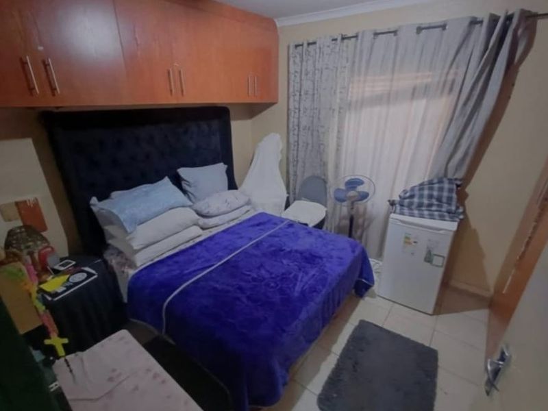 A compact bedroom featuring built-in overhead cabinetry and tiled flooring, offering functional storage space.