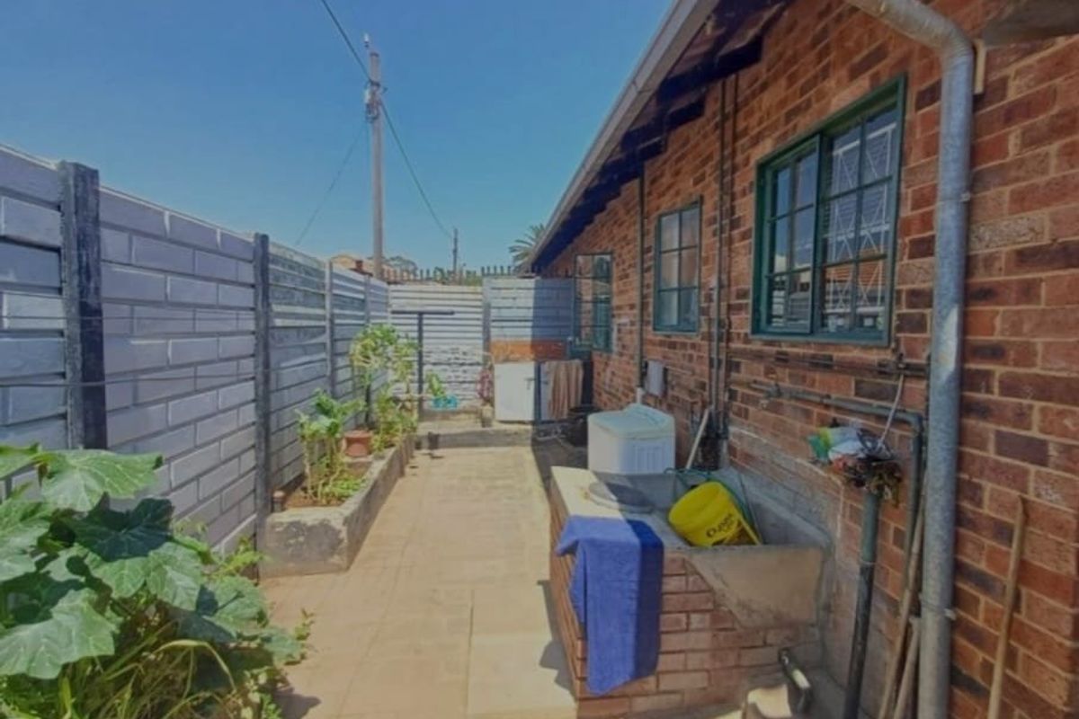 Rear exterior area featuring a brick facade, concrete laundry trough, and precast boundary walling.