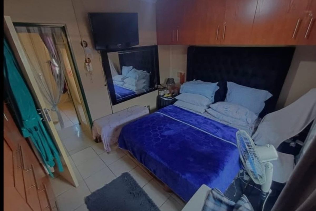A compact bedroom featuring built-in wooden cupboards and tiled flooring, providing functional storage space.