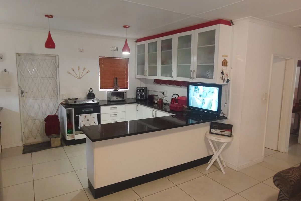 Functional kitchen featuring white cabinetry, black granite countertops, built-in oven and hob, and tiled flooring with an open-plan layout.