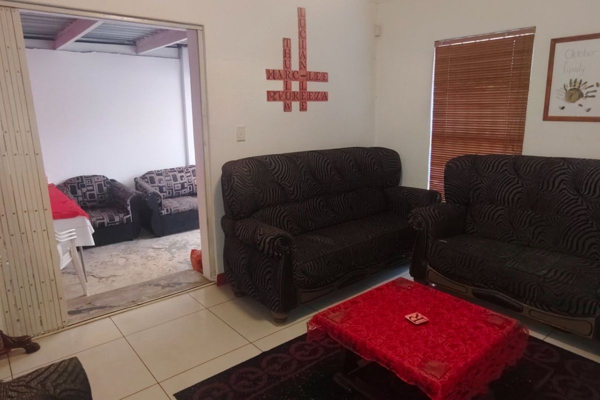 A living room area featuring tiled flooring, a folding room divider, and venetian blinds, providing a functional and connected living space.