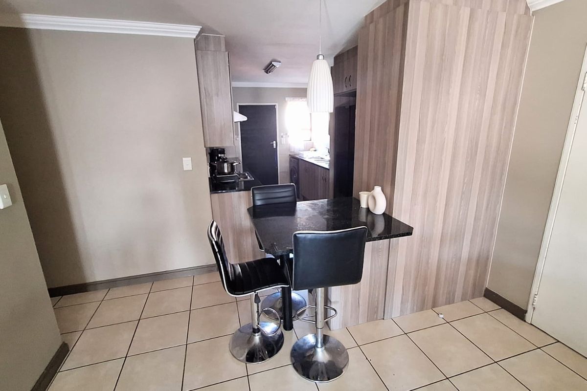 A functional kitchen area featuring wood-look cabinetry, granite countertops, tiled flooring, and a breakfast nook, providing a practical and well-maintained cooking space.