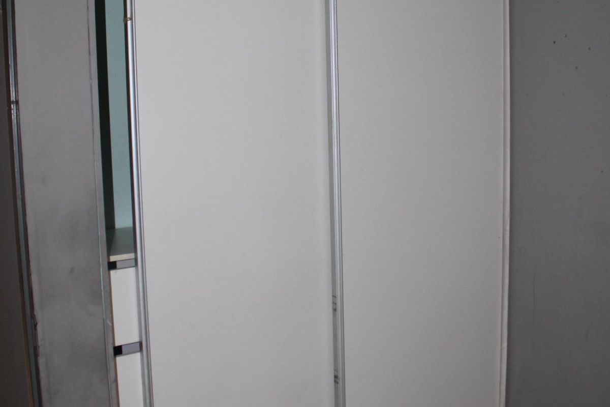 A bedroom featuring a built-in sliding door wardrobe with tiled flooring and neutral grey walls.
