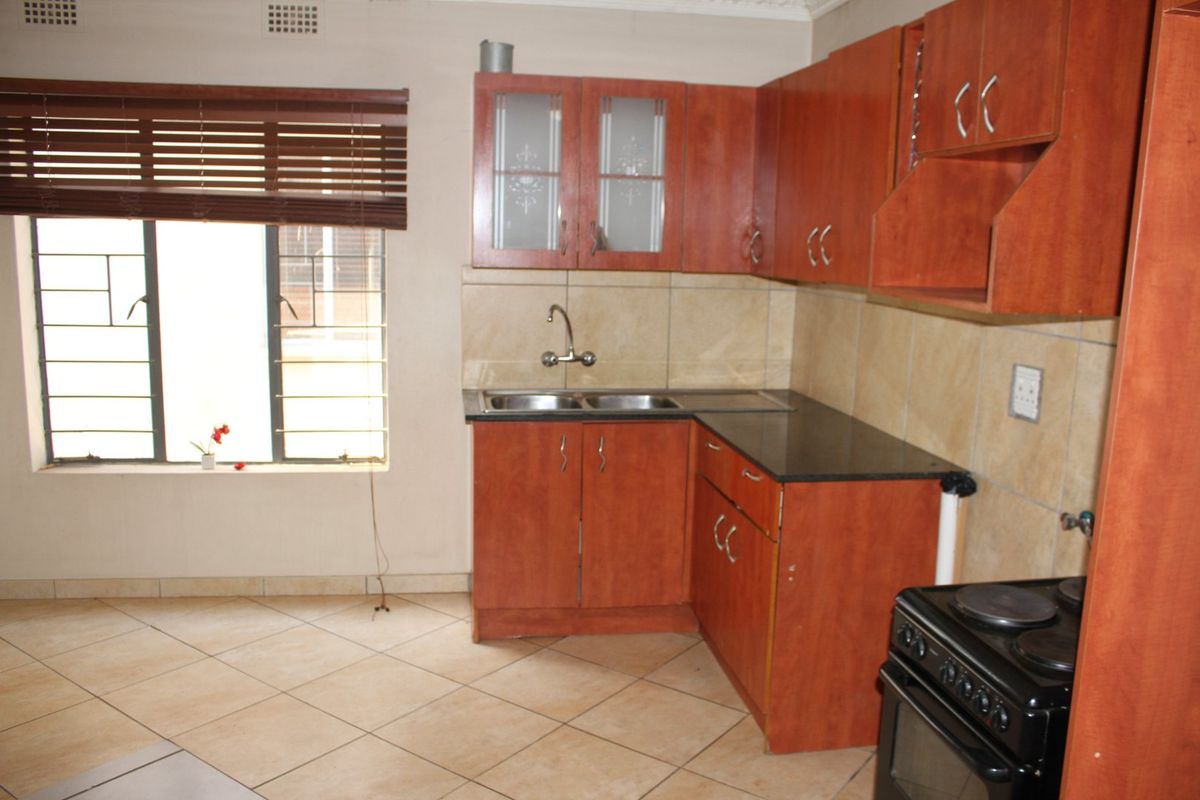 A functional kitchen featuring wooden cabinetry, granite countertops, a double basin sink, and a built-in electric stove with tiled splashbacks.
