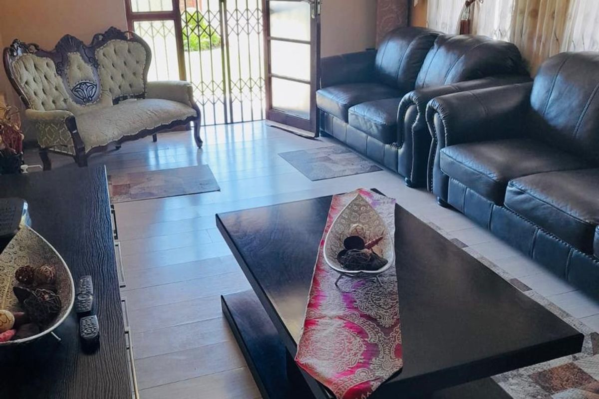 A living room featuring tiled flooring, decorative cornicing, and a security gate leading to the exterior.