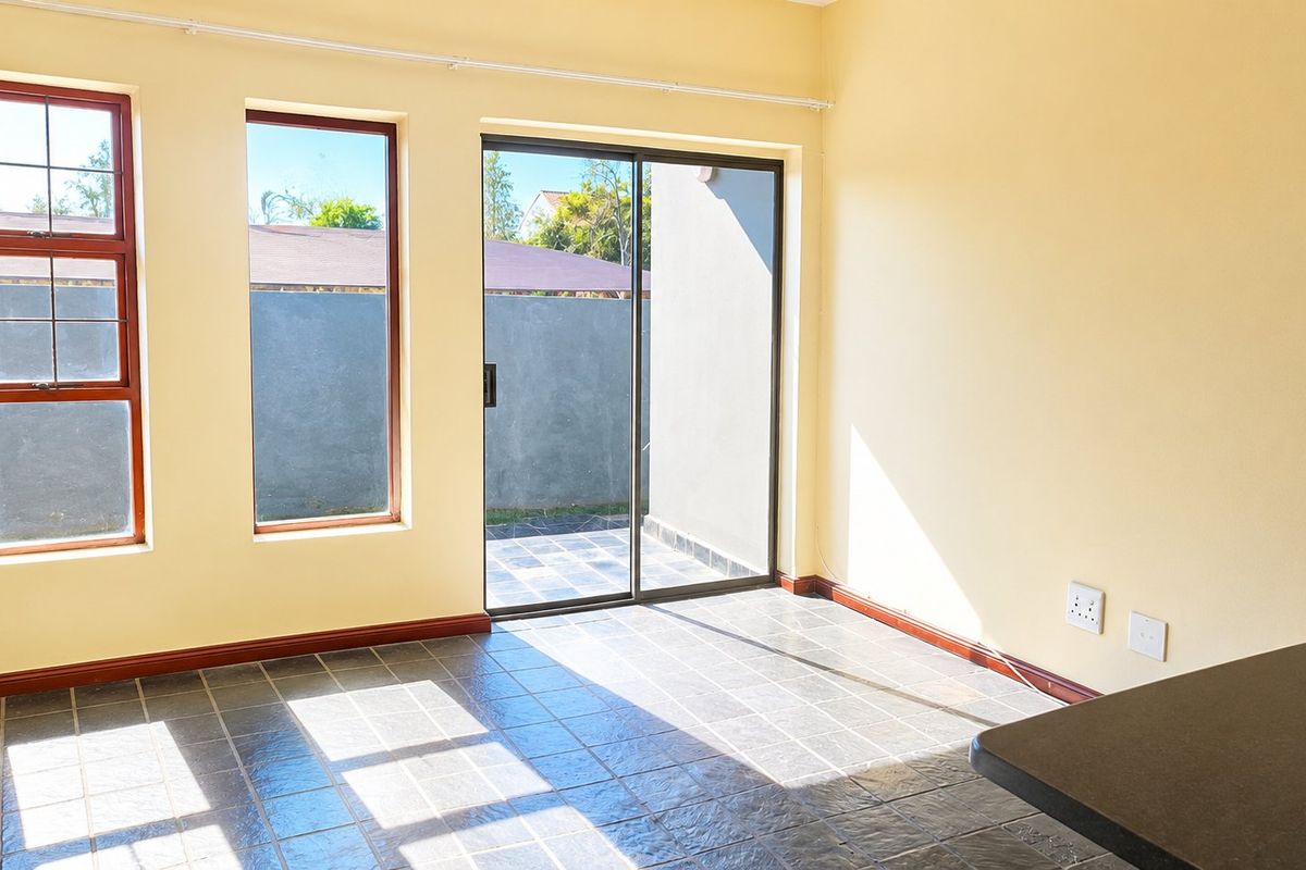 Bright open-plan living area featuring tiled flooring, large windows, and a sliding glass door providing direct access to the outdoor space.
