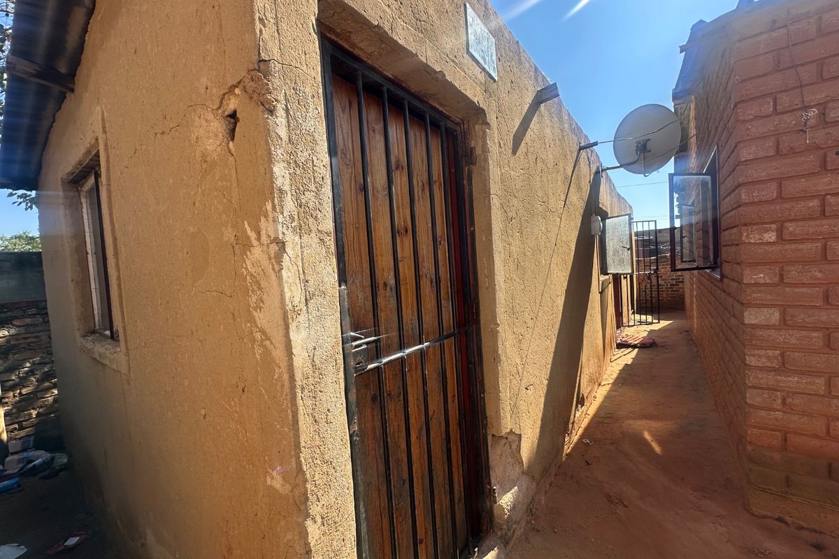 Side passage view showing exterior wall finishes, security gate, and satellite dish installation on a residential property.