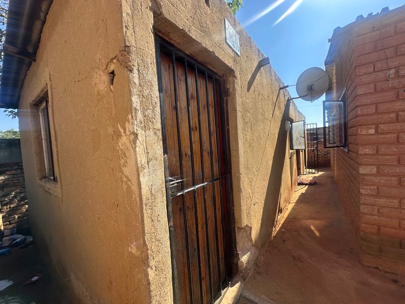Side passage view showing exterior wall finishes, security gate, and satellite dish installation on a residential property.