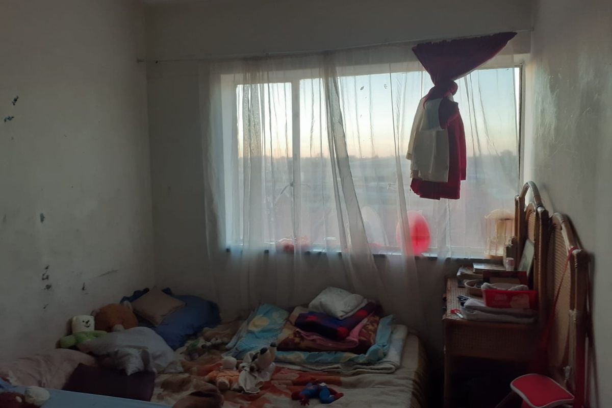 A bedroom featuring a large window with natural light, requiring cosmetic updates to the wall finishes to improve the overall condition.