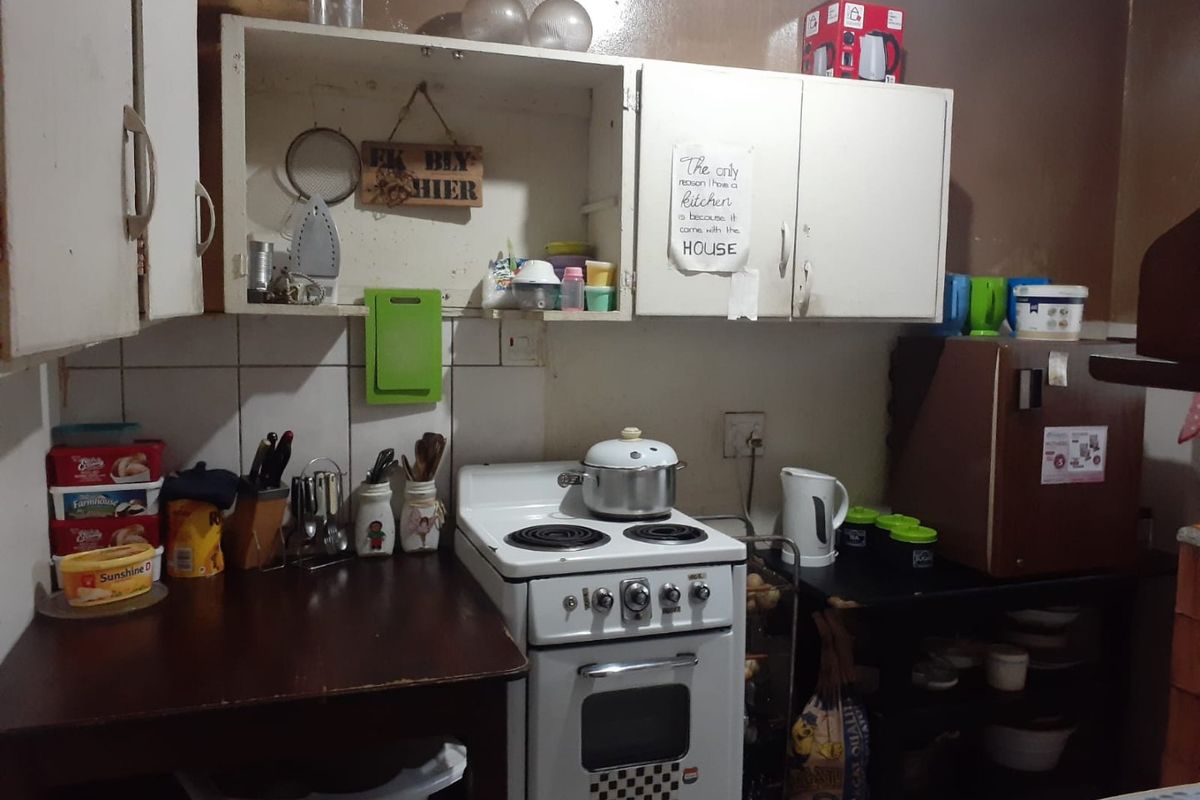 A compact kitchen featuring dated cabinetry, a tiled backsplash, and a freestanding stove, offering potential for modernization and improved layout efficiency.