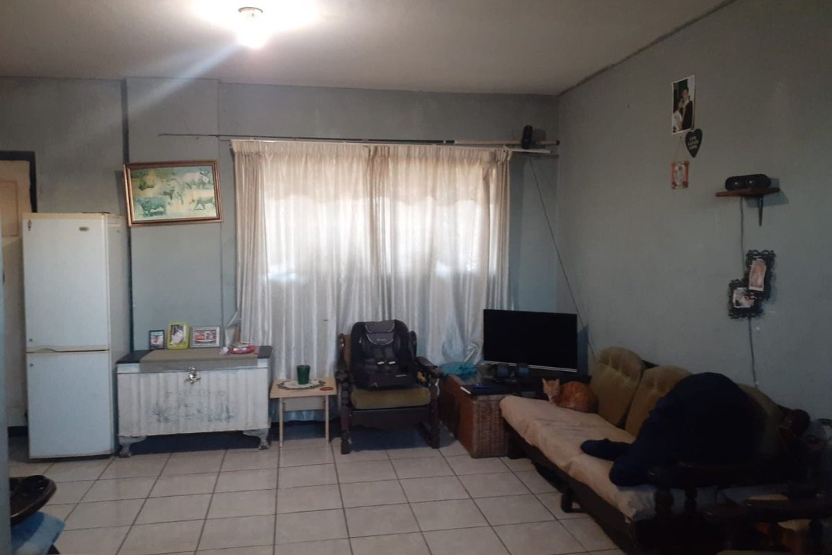 A living room area featuring ceramic floor tiles and neutral wall finishes, offering a functional space ready for modernization and aesthetic updates.